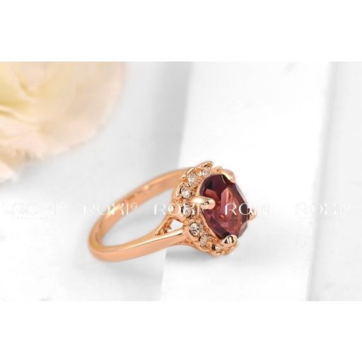 Aranyozott gyűrű, nagy alakú csiszolt bordó-lilás kővel, körülötte apró cirkóniummal